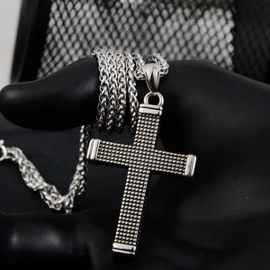 Macro view of vintage silver cross pendant with dotted texture and wheat chain detail