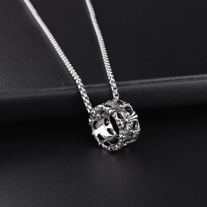 Macro shot of silver ring pendant with engraved Gothic cross pattern and box chain