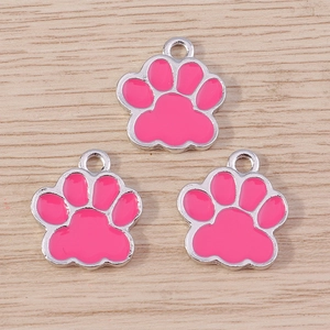 Three pink cat paw alloy charms with silver trim for DIY jewelry making on wood background