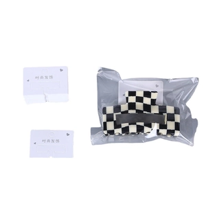 Checkerboard pattern hair claw clip with white cardboard packaging tags in black and white