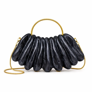 Macro view of wave-shaped acrylic evening bag with marble texture and gold metal ring handle