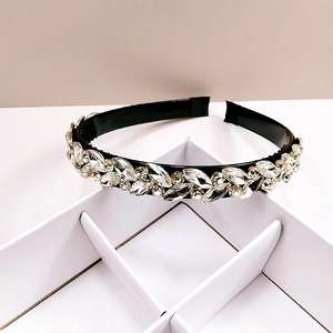 Close-up of sparkling crystals and rhinestones on a wide black padded headband base