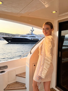 Champagne sequin party dress with dramatic ruffled shoulder on a luxury yacht