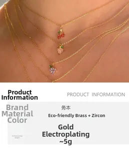 Détail de colliers dorés superposés avec pendentifs cerise et pêche en zircon coloré