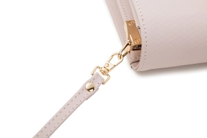 Detail of pink cross-grain leather texture and golden metal hook on crossbody bag