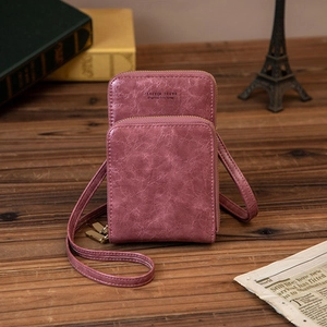 Vue détaillée du sac à bandoulière rose en cuir ciré avec double fermeture sur table bois