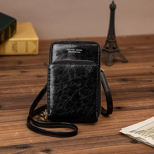 Détail du sac de téléphone en cuir huilé noir avec texte Forever Young sur fond en bois
