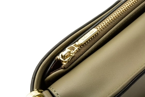 Close-up of golden zipper and fine edge stitching on green leather crossbody phone bag