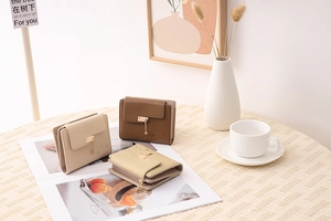 Detailed view of three mini tri-fold wallets in brown, cream, and sage green with heart charms