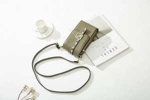 Detail of dark green phone bag with leaf buckle and adjustable shoulder strap