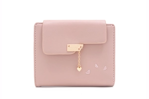 Detail view of pink trifold wallet with heart embroidery and metallic heart charm pendant