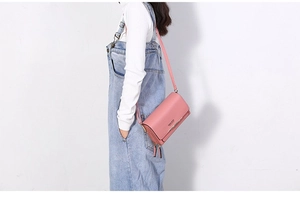 Pink PU leather crossbody phone bag shown on a model with white top and denim overalls