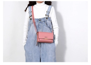 Pink PU leather crossbody bag with metal bar detail worn by a model in casual style