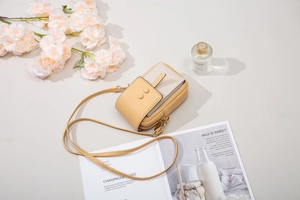 Detalle del bolso de móvil amarillo y beige con bandolera y cierres metálicos de calidad