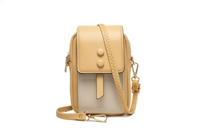Detalle del bolso bandolera amarillo claro y beige con textura de cuero y hebillas redondas