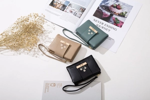 Three-color floral wallets with daisy prints and golden clasp in an elegant still life