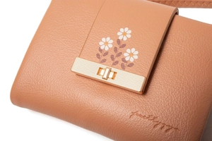 Detailed close-up of brown pebble leather wallet with daisy prints and gold buckle