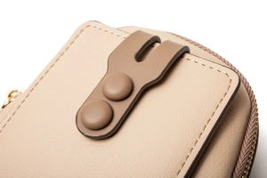 Detail of beige leather phone bag showing double snap closure and fine stitching craft