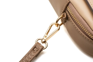 Close-up of golden metal zipper and buckle on a taupe leather crossbody phone bag