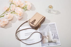 Detail view of small crossbody phone bag with zip compartment and magnetic flap closure
