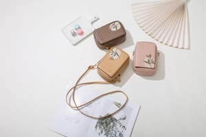 Detailed view of mini crossbody bags with leaf embroidery and elegant lifestyle props
