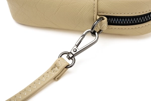 Gros plan détaillé d'un sac à bandoulière en cuir beige avec fermeture éclair gris foncé