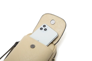 Détail de la pochette téléphone beige montrant la texture grainée et le fermoir aimanté