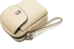 Gros plan sur un sac bandoulière beige en cuir grainé avec logo métal et dragonne chic