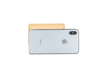 Detailed view of yellow lychee leather wallet next to an iPhone for size comparison