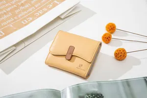 Close-up of yellow tri-fold wallet with floral embossed clasp and litchi texture