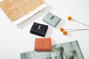 Three-fold leather wallets in black, blue and orange shown with lifestyle props