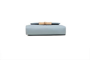 Detail view of light blue PU leather wallet with golden buckle and white stitching