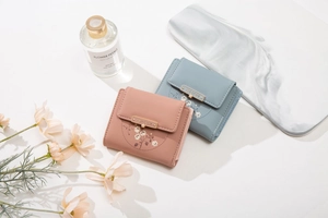 Close-up of floral PU leather wallets in pink and blue with gold brand metal bars