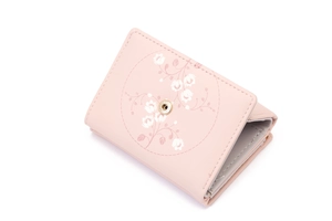 Detail view of pink PU leather tri-fold wallet with white floral print and gold snap closure