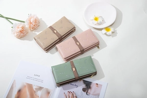 Detail of embroidered leaf pattern and golden buckle on three colors of long wallets