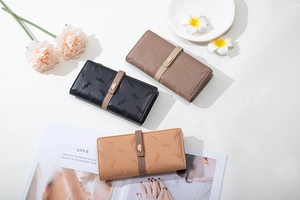 Detailed view of three embroidered soft leather wallets in black, taupe and tan shades