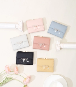 Flat lay of multiple pastel floral PU leather trifold wallets with metal snap closures