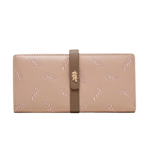 Detail of leaf embroidery and golden metal leaf ornament on a soft pink leather wallet