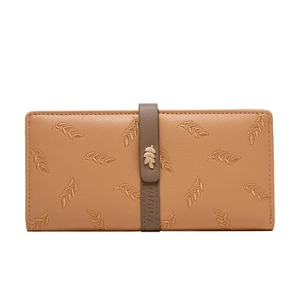 Detail showing embroidered leaf pattern and metal leaf buckle on light brown wallet