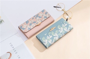 Detail of long floral PU leather wallets in pink and blue with gold metallic accents