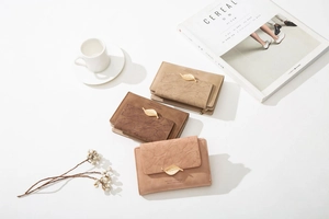 Detailed view of women's wallets with leaf metal buckle in light khaki and pink tones