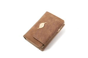 Detail of matte brown faux leather wallet with golden leaf charm and embossed veins