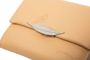 Close-up of beige leather wallet featuring silver leaf metal trim and embossed details