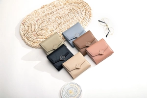 Close-up of compact leather wallets in six colors with clover metal clasps on white background