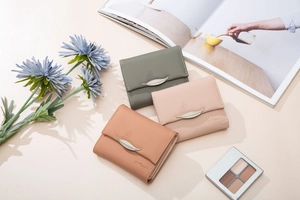 Detailed view of three trifold faux leather wallets with metal leaf buckles and soft colors