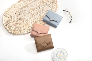 Three compact leather tri-fold wallets in pastel shades with clover magnetic buckles