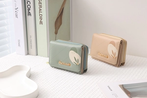 Dettaglio di portafogli in ecopelle trapuntata verde salvia e beige con motivi botanici