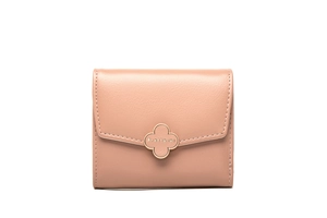 Detail of a dusty pink leather wallet featuring a gold four-leaf clover magnetic clasp