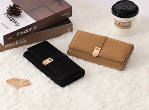 Detailed view of long PU leather wallets with gold buckles on a cozy white plush rug