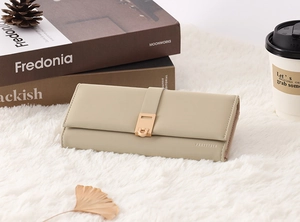 Pale green long PU leather wallet featuring gold metal buckle on white faux fur background